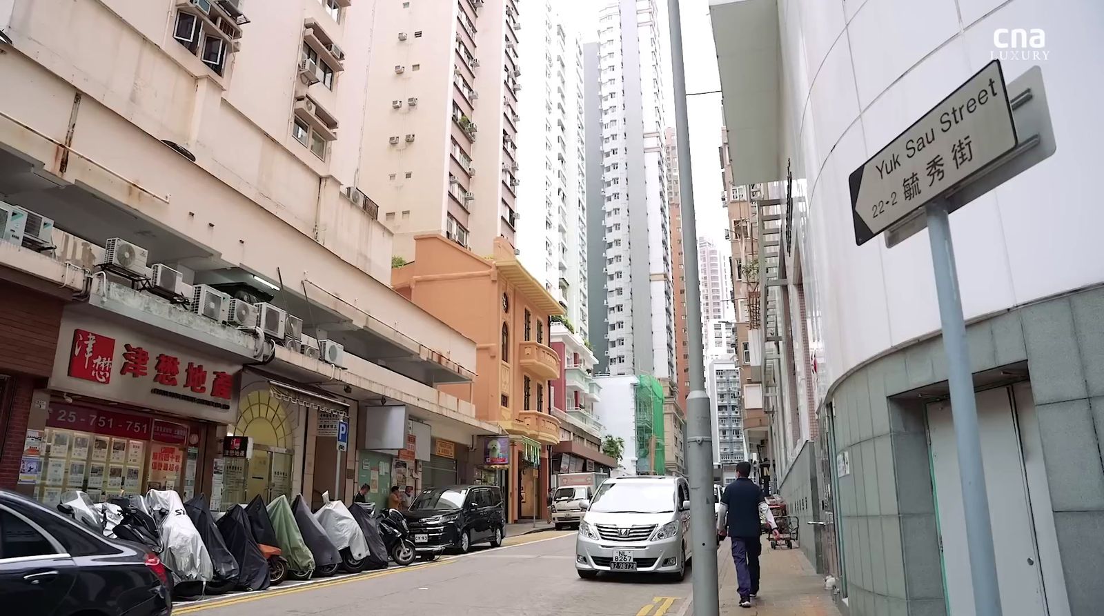 a man walking down a street next to tall buildings