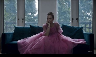 a woman in a pink dress sitting on a couch