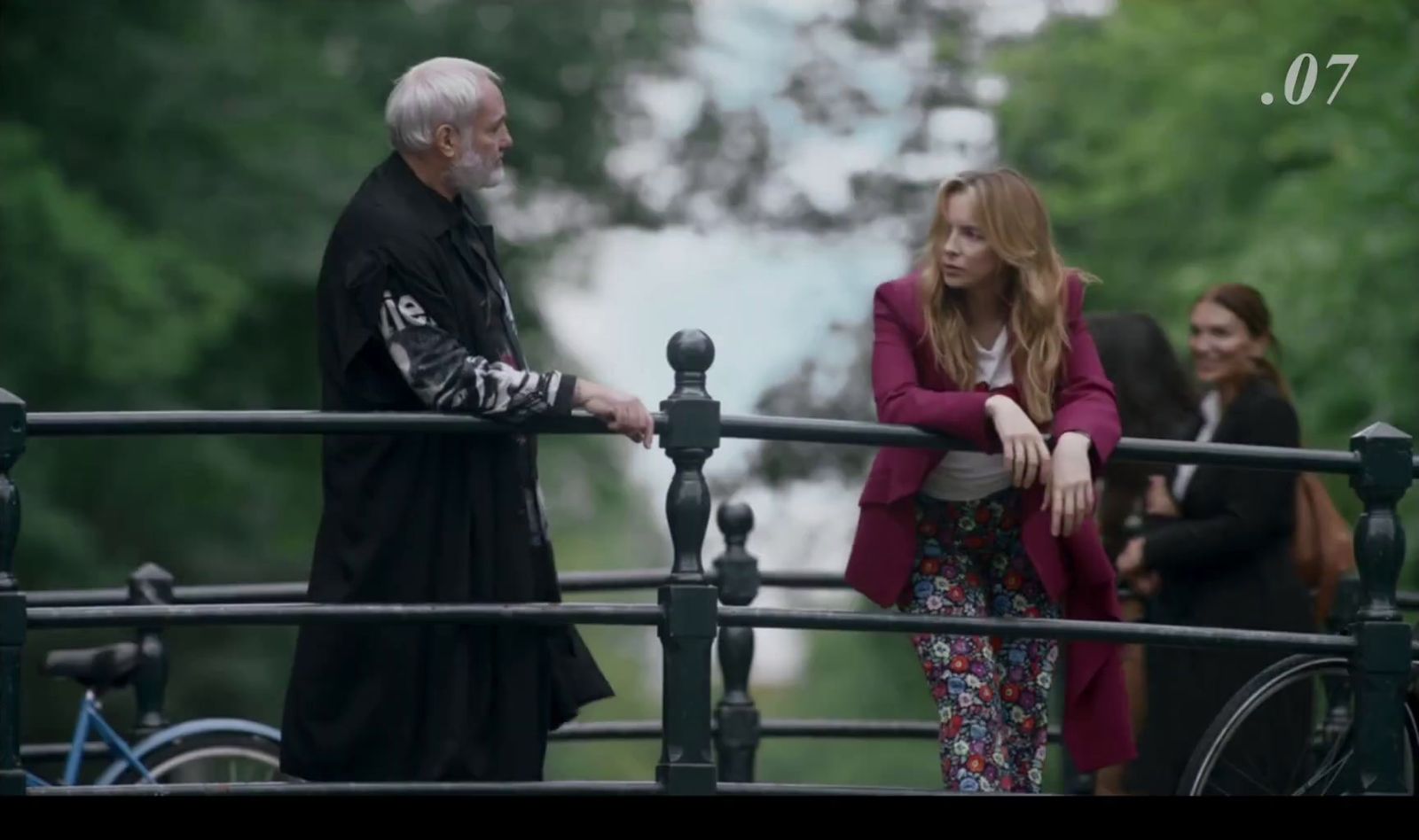 a man standing next to a woman on a bridge