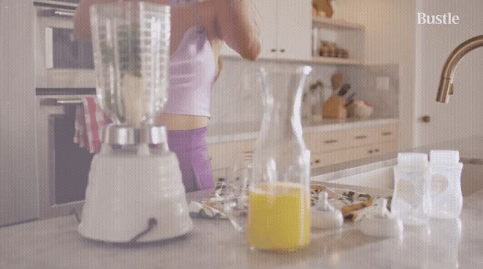 a woman standing in a kitchen next to a blender