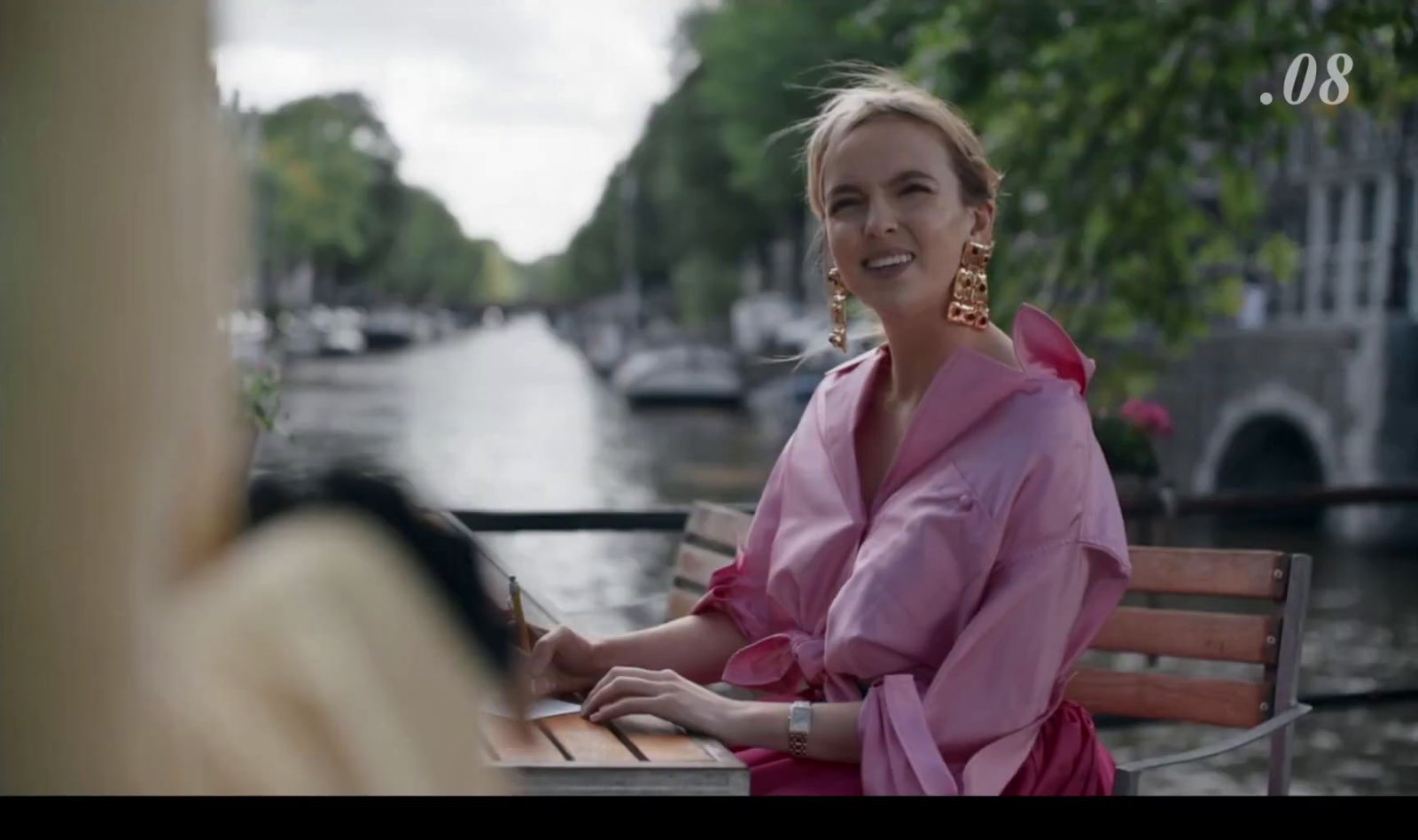 a woman sitting on a bench next to a river