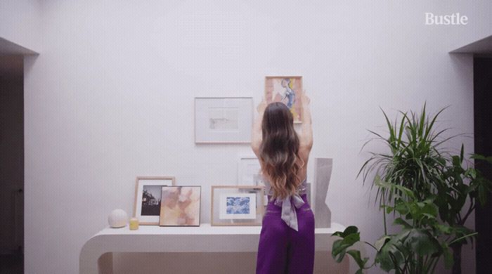 a little girl standing in front of a wall with pictures on it