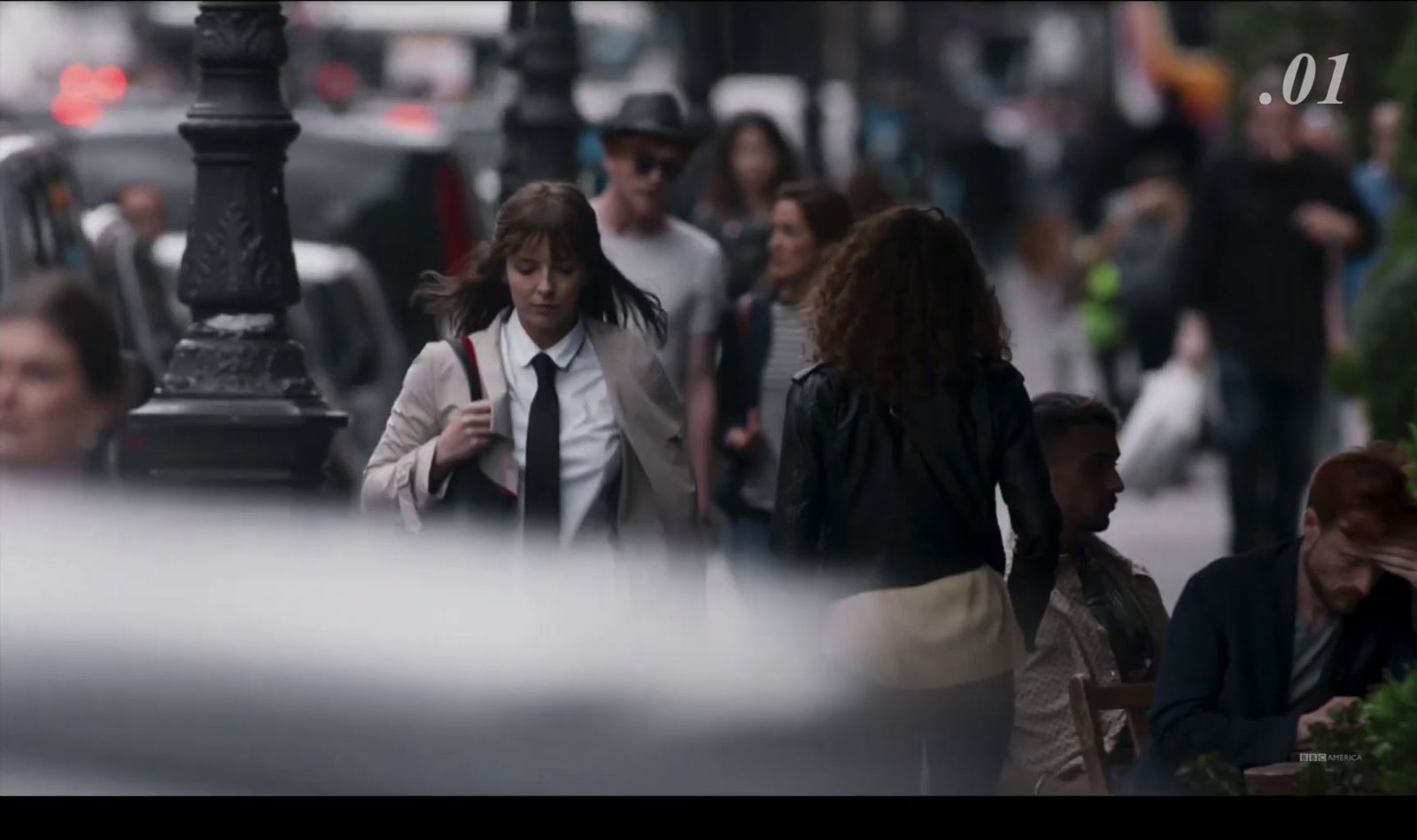 a group of people walking down a street next to a lamp post