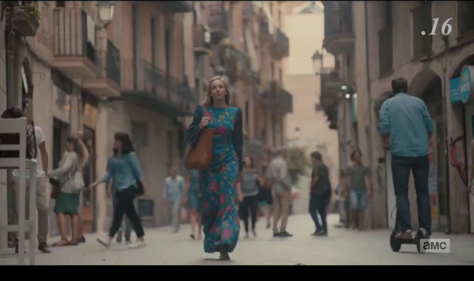 a woman walking down a street next to tall buildings