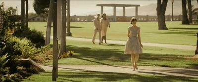 a woman in a dress walking down a sidewalk