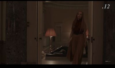 a woman in a long dress walking into a room