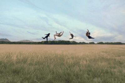 three people jumping in the air in a field