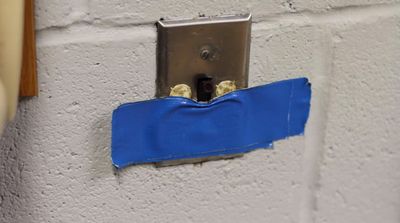 a piece of blue tape is taped to a white brick wall