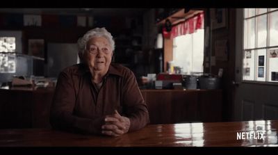 an old man sitting at a table in a restaurant