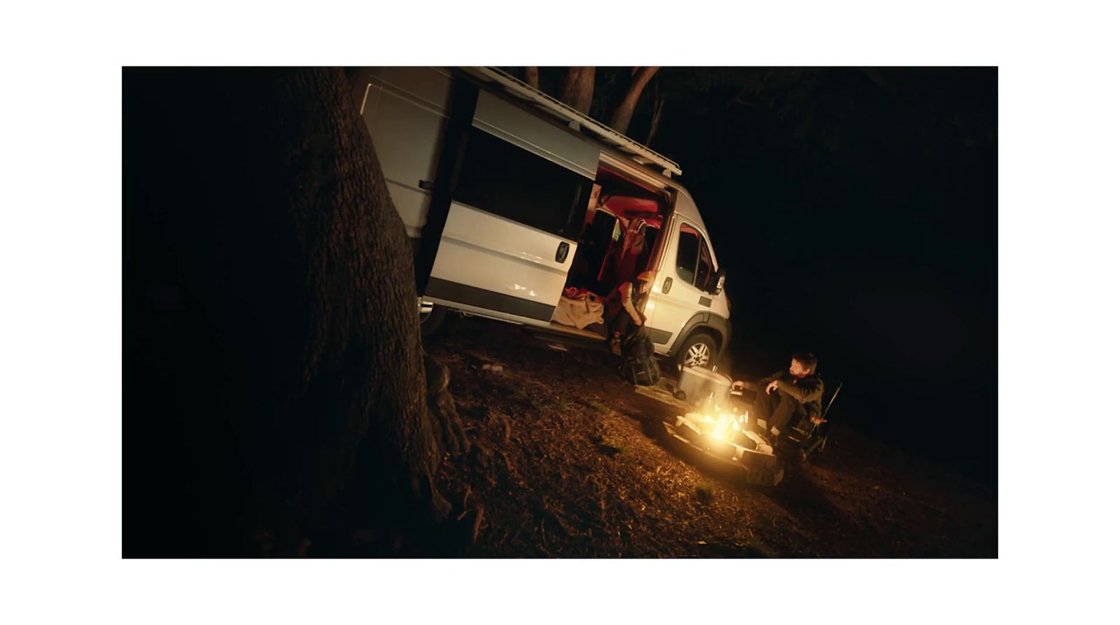 a white van parked next to a tree in the dark