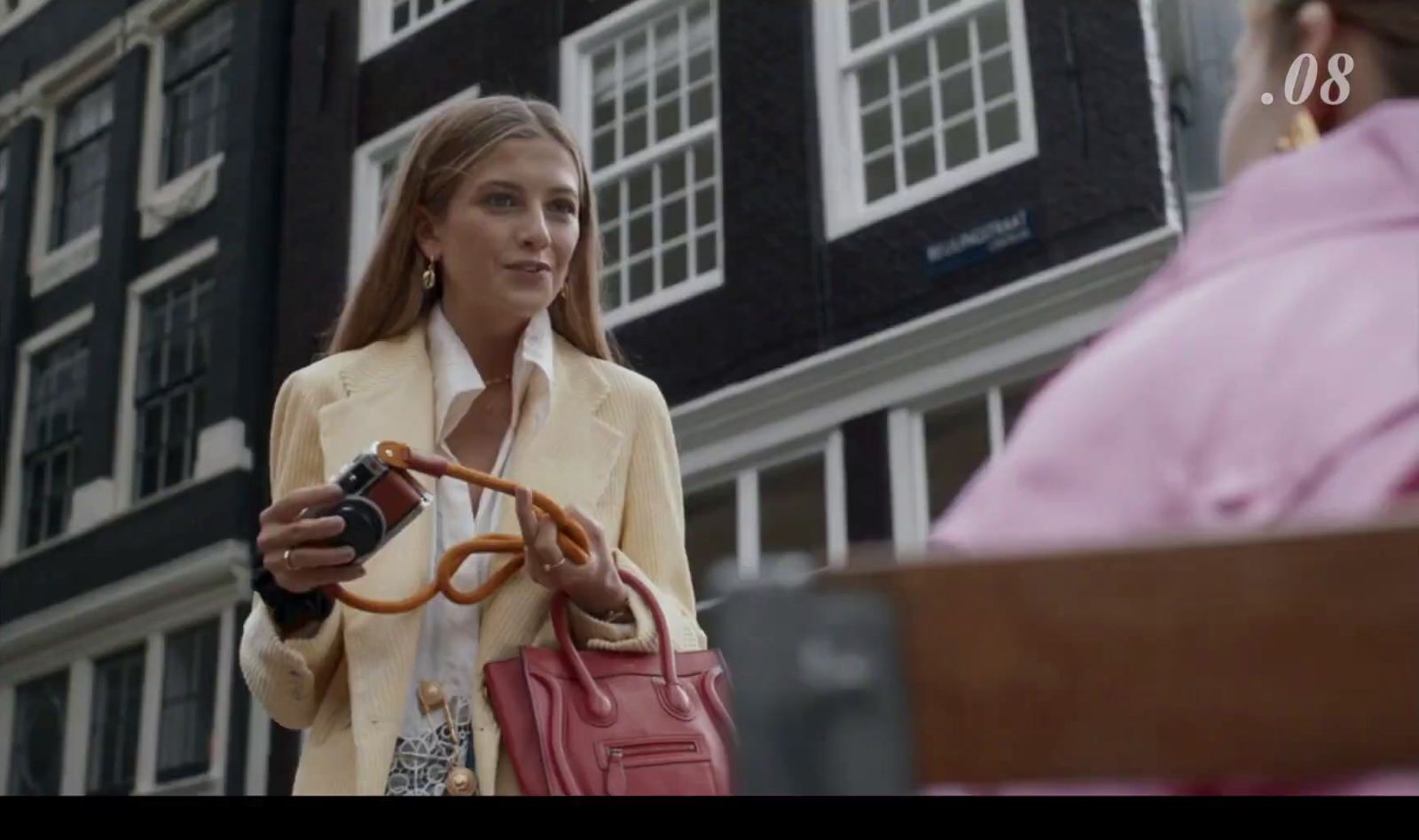 a woman holding a camera and a pink purse