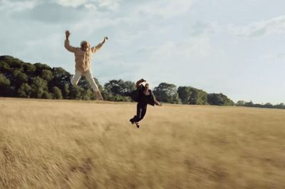 two people jumping in the air in a field