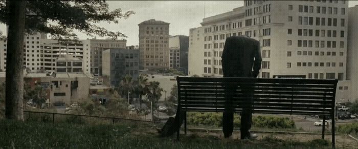 a man in a suit sitting on a park bench