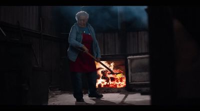 a woman in a red apron holding a large stick