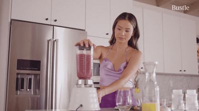 a woman standing in a kitchen with a blender