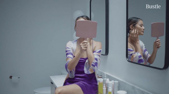 a woman in a purple dress sitting in front of a mirror