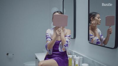 a woman in a purple dress sitting in front of a mirror