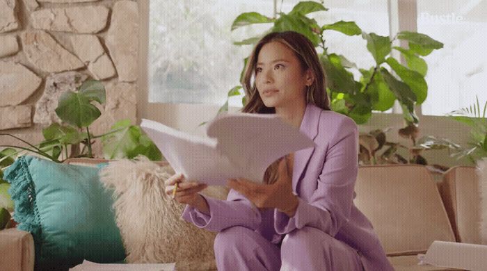 a woman sitting on a couch reading a piece of paper