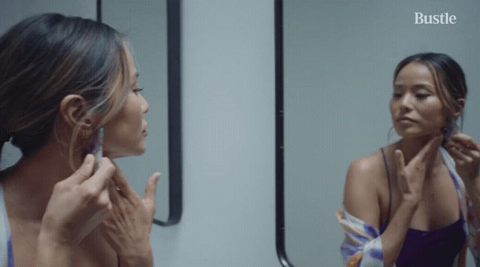 a woman standing in front of a mirror brushing her teeth