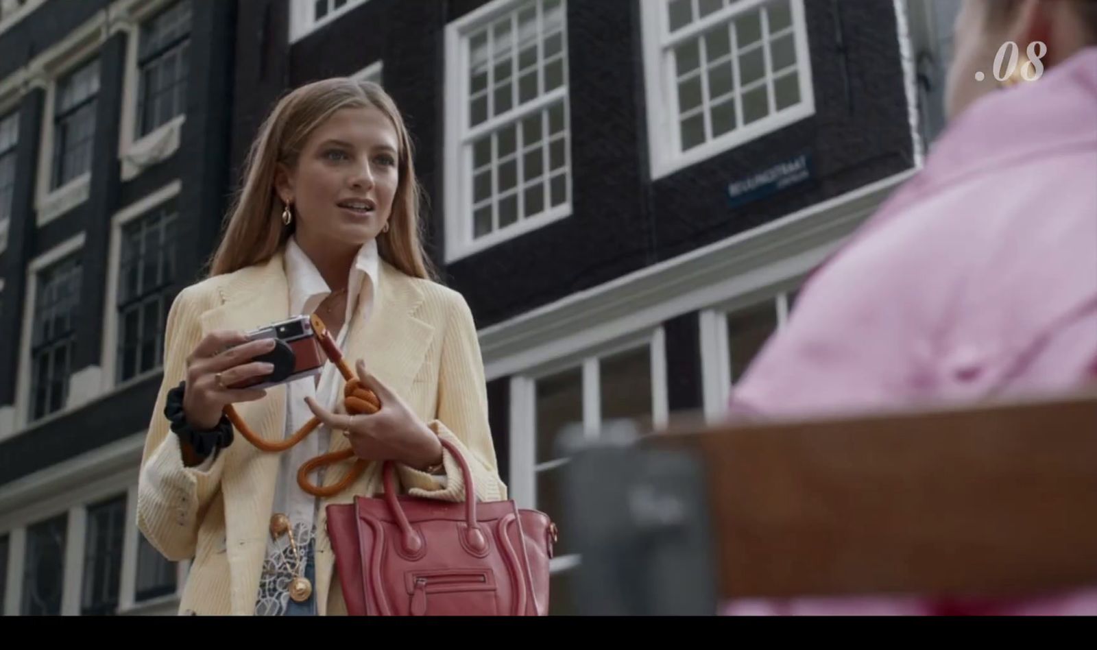 a woman is holding a camera and a purse