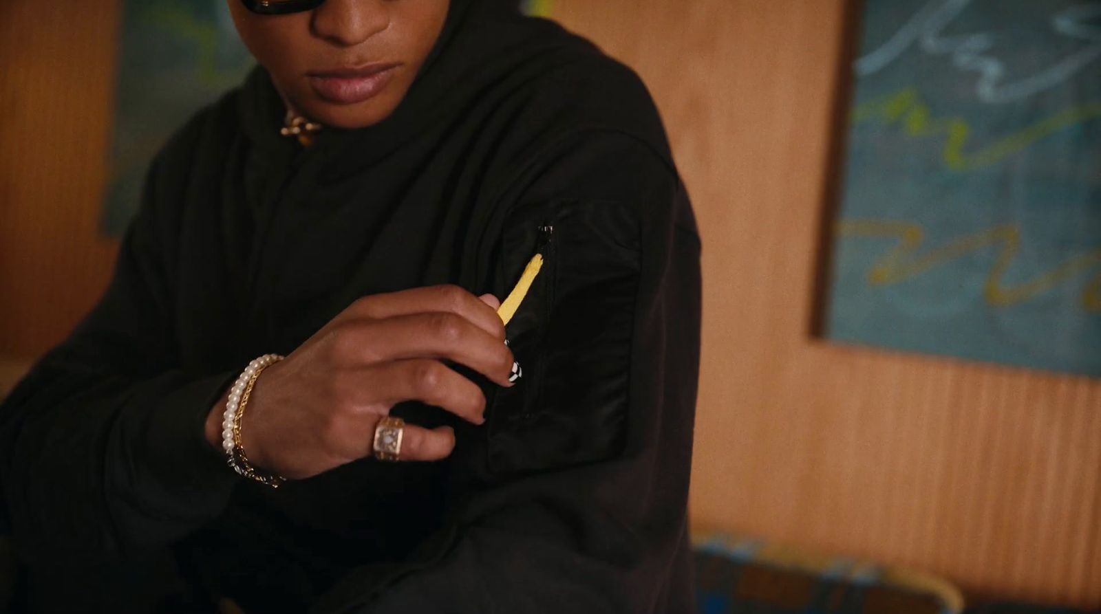 a man in a black hoodie holding a yellow pen