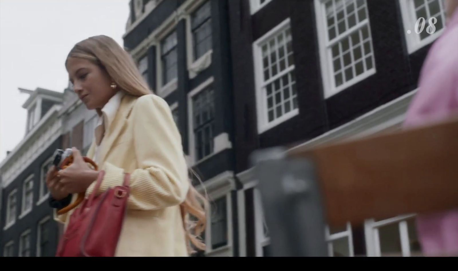 a woman standing in front of a building looking at her cell phone