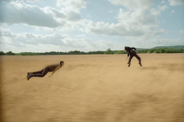 two people jumping in the air in a field