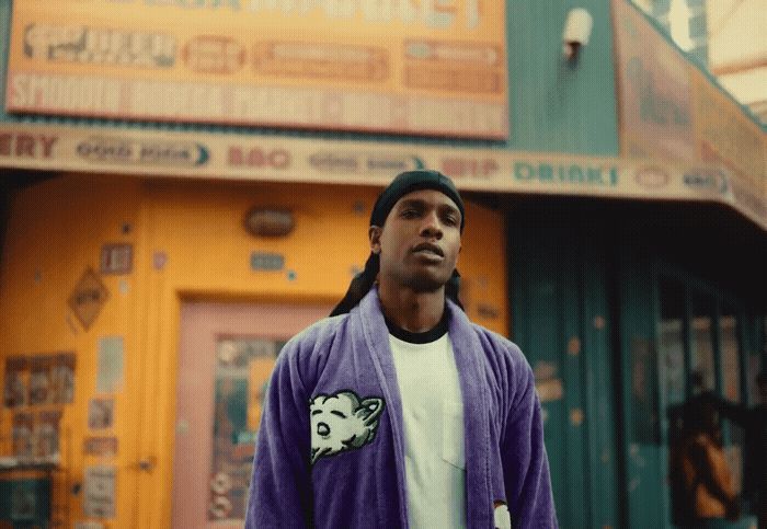 a man in a purple jacket standing in front of a building