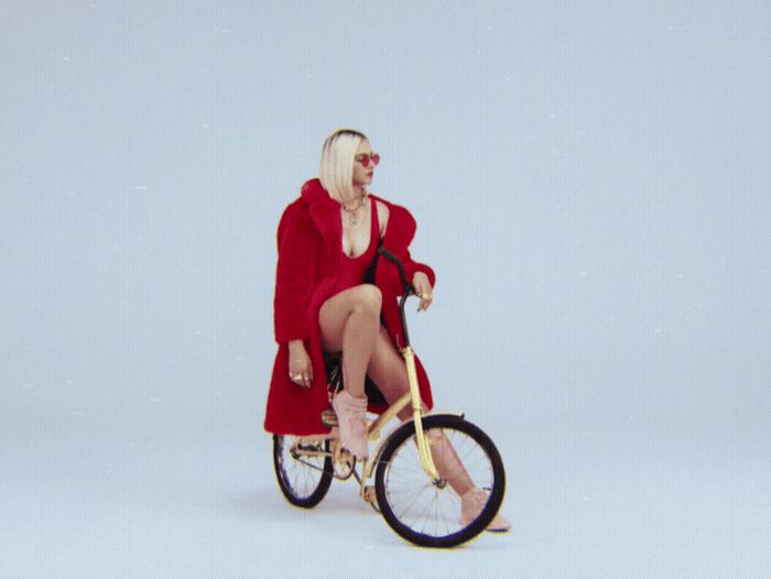 a woman in a red coat is riding a bike