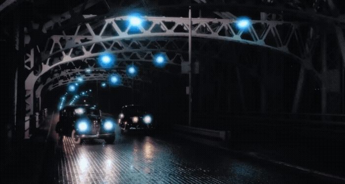 a couple of cars driving down a street at night