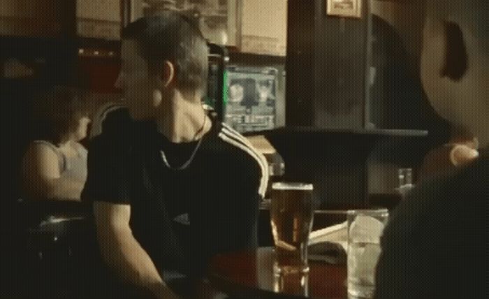 a man sitting at a bar with a glass of beer