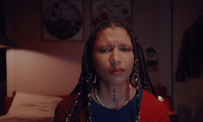 a woman with dreadlocks standing in front of a bed