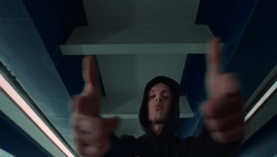 a man in a black hoodie holding up two fingers