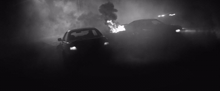 a black and white photo of a car on fire