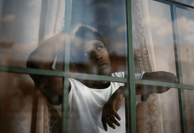 a woman looking out of a window with her hands on her head