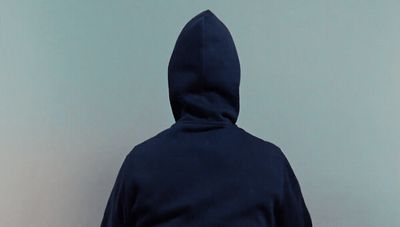 a person in a blue hoodie standing against a wall