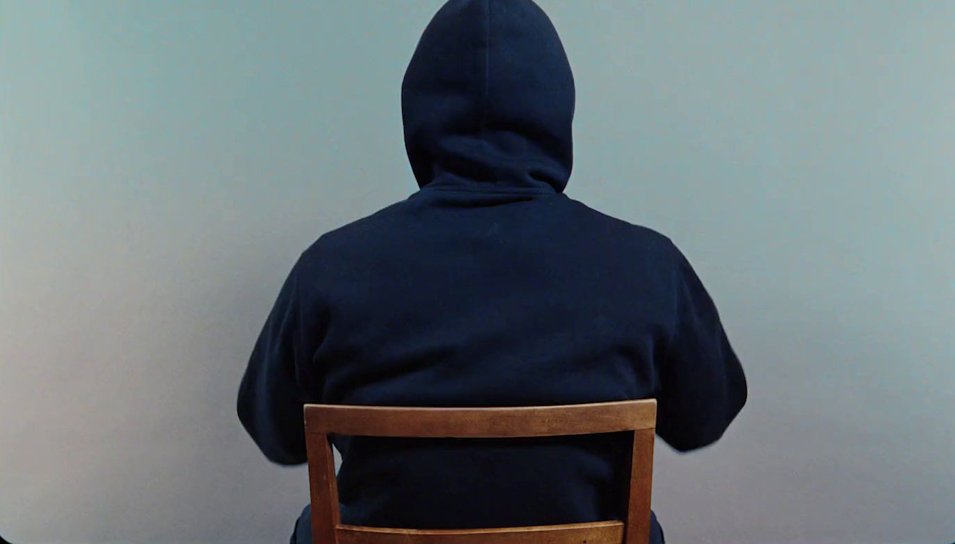 a person sitting in a chair with a hoodie on