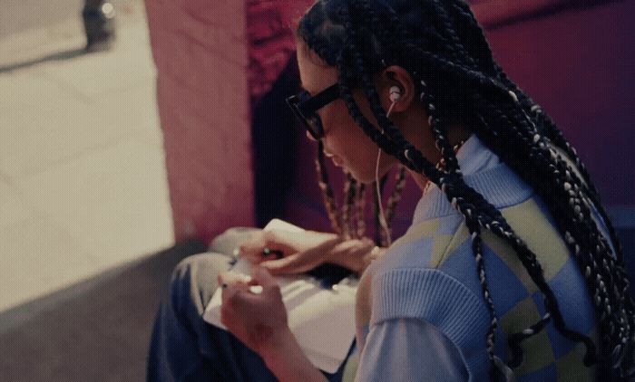 a woman with dreadlocks sitting on a bench looking at her cell phone