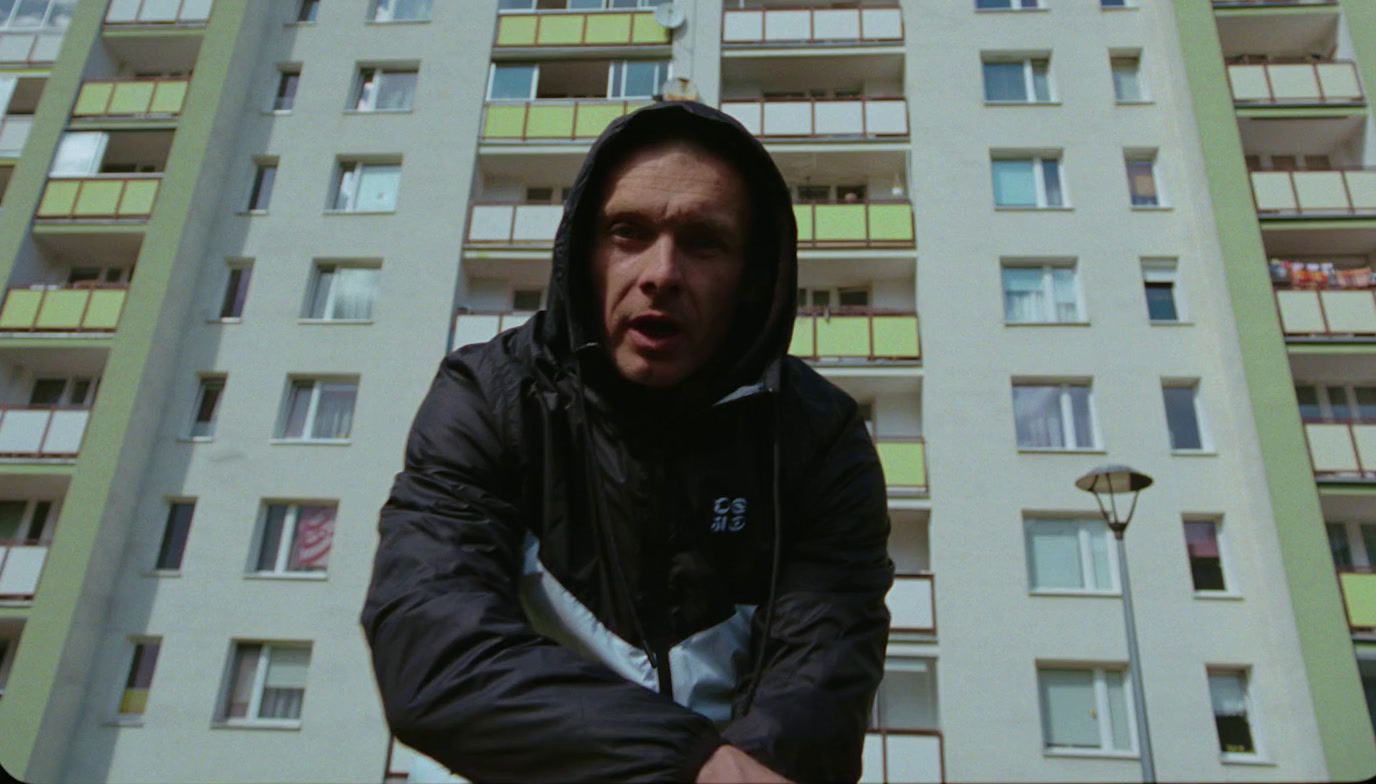 a man in a hoodie standing in front of a tall building