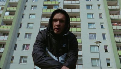 a man in a hoodie standing in front of a tall building