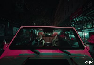 a pink car parked on the side of a street at night