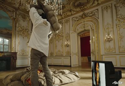 a man standing on a bed in a room with a chandelier