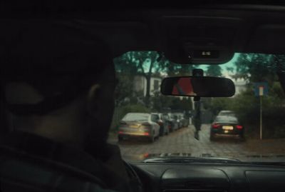 a man driving a car down a street next to a forest