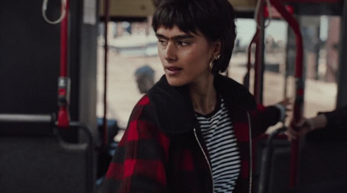 a woman in a red and black jacket standing on a bus