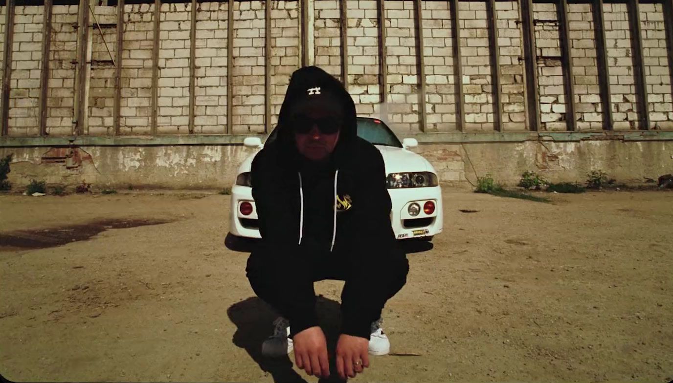 a man kneeling down in front of a white car