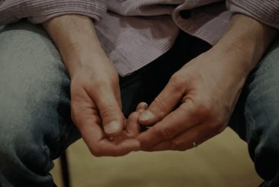 a man sitting down holding his hands together