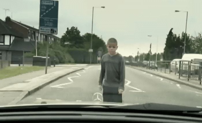 a young man standing on the side of a road