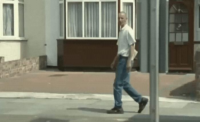 a man walking down a street past a building