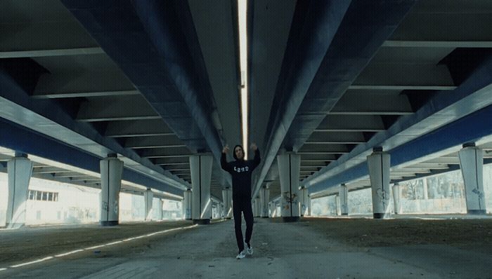 a person standing under a bridge with their arms in the air