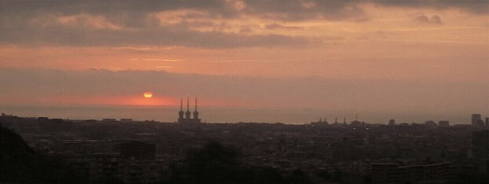 the sun is setting over a city with tall buildings